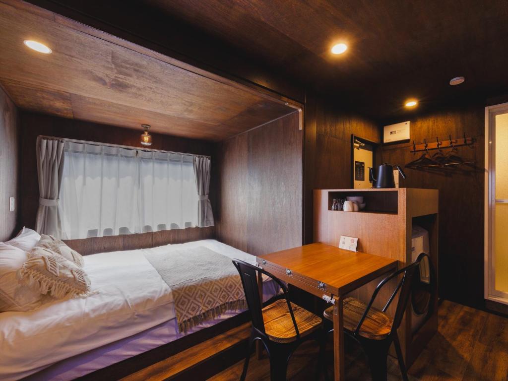 a bedroom with a bed and a table and a window at Seage Torami Coastside in Ichinomiya