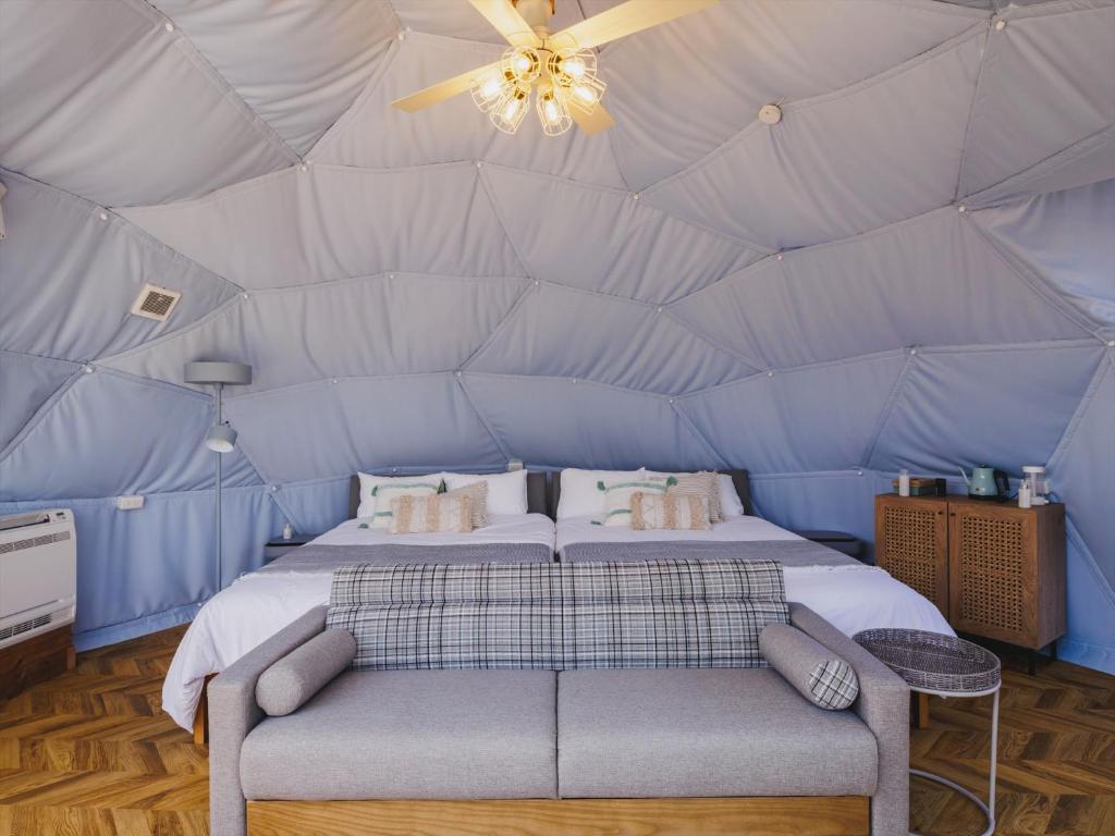 a bedroom in a dome tent with a bed and a couch at Seage Torami Coastside in Ichinomiya