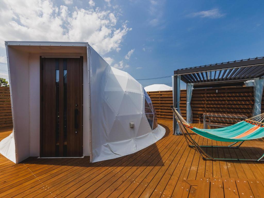 a tent on top of a deck with a hammock at Seage Torami Coastside in Ichinomiya