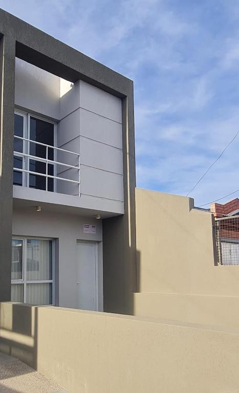 a white house with a balcony on top of a fence at Duplex Portugal Tw in Trelew