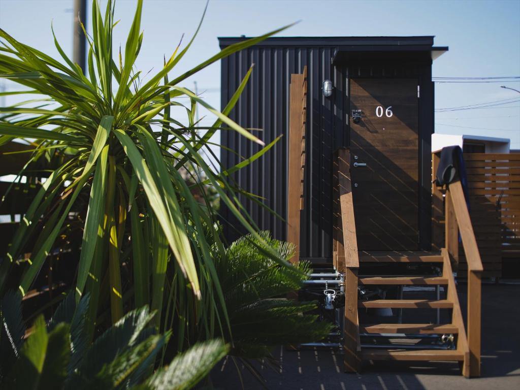 a house with a black door and some plants at Seage Torami Coastside in Ichinomiya
