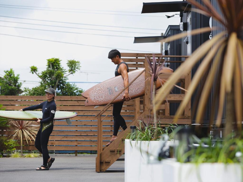 two men in wet suits carrying their surfboards at Seage Torami Coastside in Ichinomiya