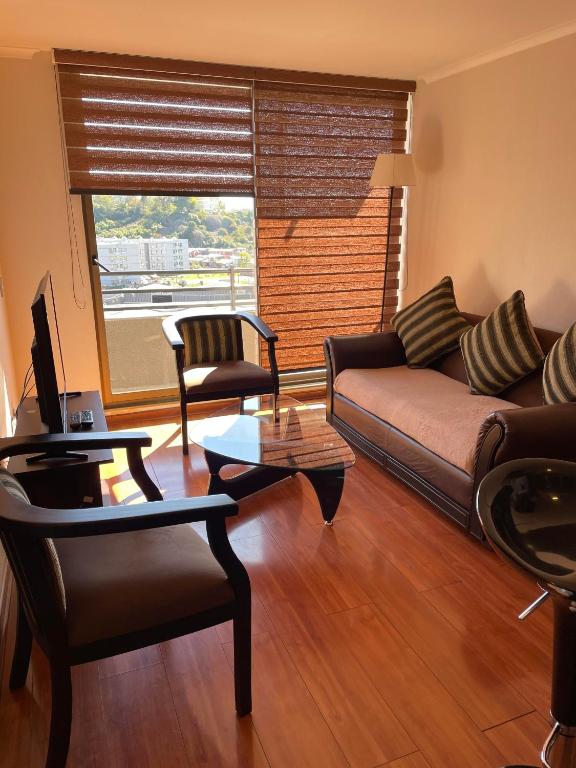 a living room with a couch and chairs and a window at Departamento Aníbal Pinto Concepción in Concepción