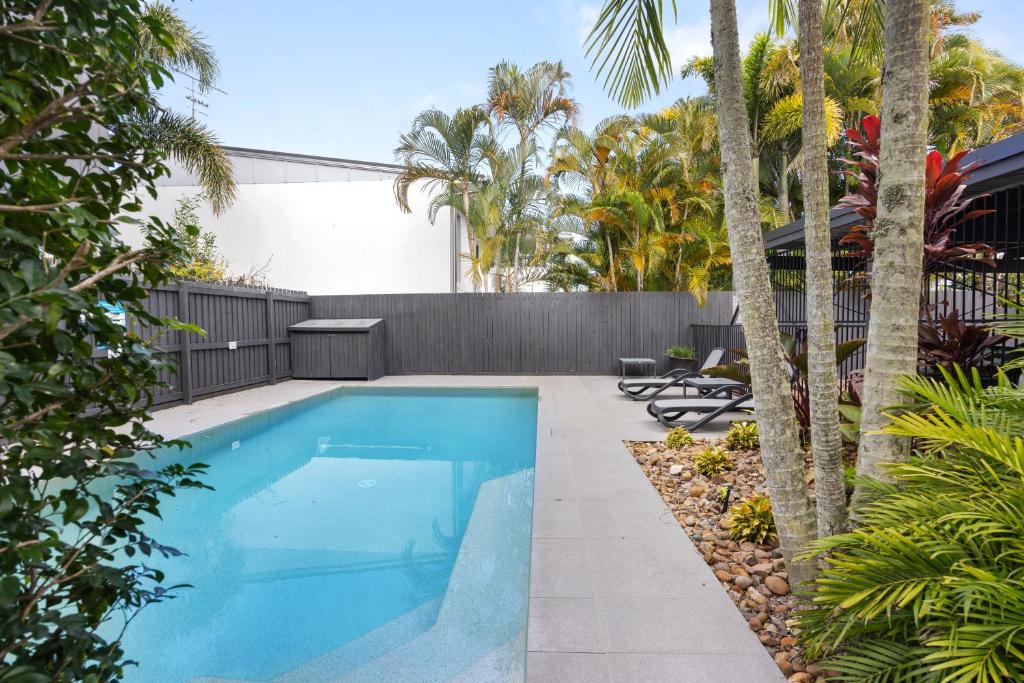 a swimming pool in a yard with palm trees at Moondarah: Pet-Friendly Escape in Noosa Heads