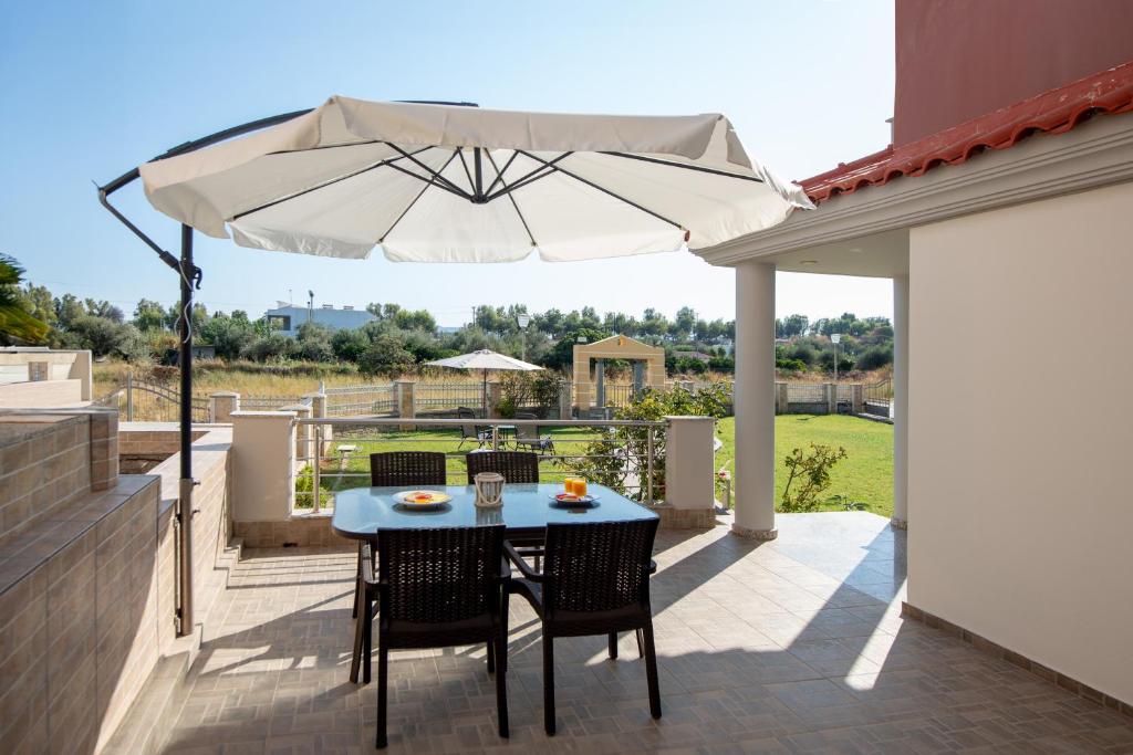 een tafel en stoelen met een parasol op een terras bij Katerina Apartment in Afantou