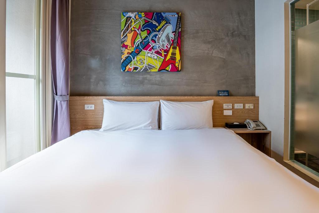 um quarto com uma cama branca e uma pintura na parede em CHECK inn Express Taichung Yizhong em Taichung