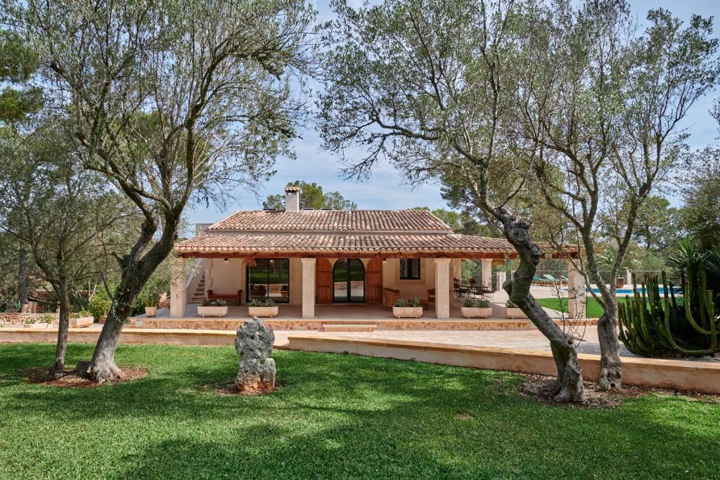a building in a park with trees in the foreground at Finca Ses Rotes in Cala Ferrera