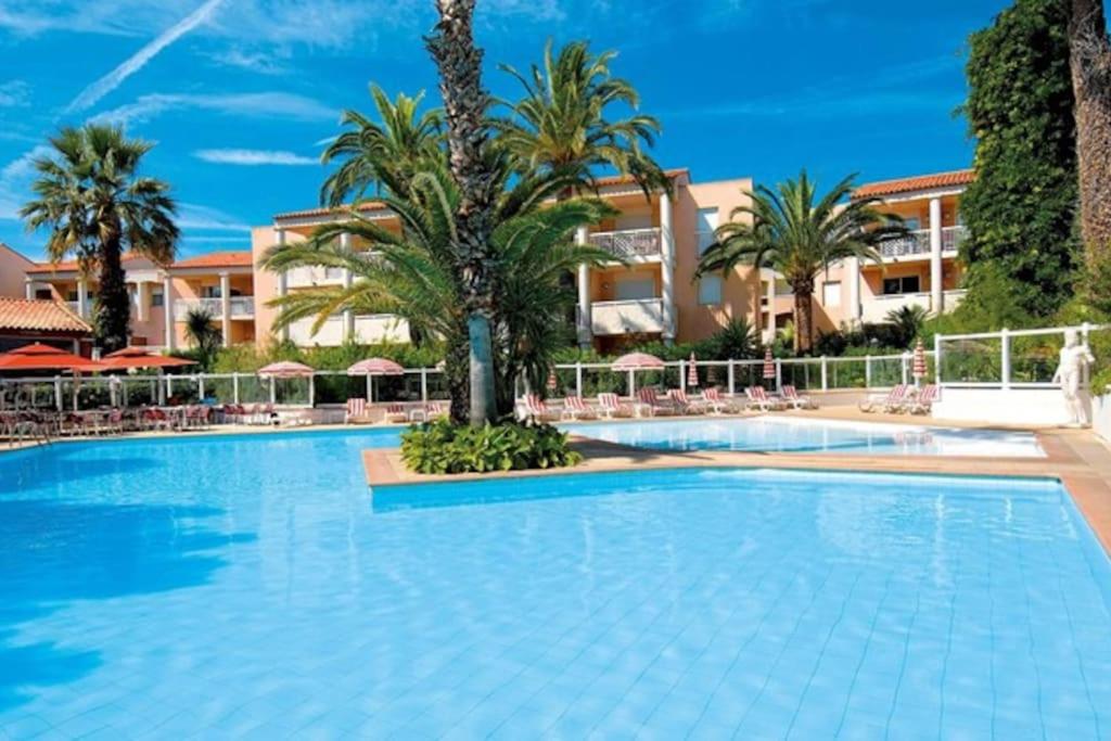 une grande piscine avec des palmiers et un bâtiment dans l'établissement Agreable et Calme 3 pieces Terrasse, Piscine, Tennis, Plage, à Vallauris