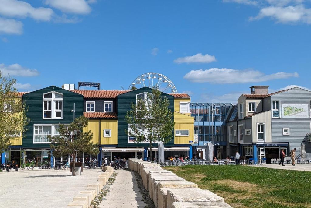 une rangée de bâtiments colorés avec une roue ferris en arrière-plan dans l'établissement Charming Apartment in La Rochelle for 4p, à La Rochelle