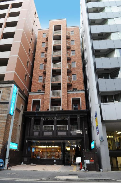 an apartment building in front of two tall buildings at Anchor Hotel Hakata in Fukuoka