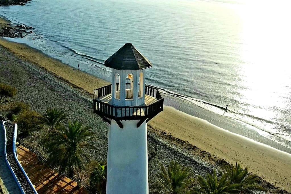 a lighthouse on the beach next to the ocean at Vivienda Vacacional frente al mar Playa del Aguila in Playa del Aguila