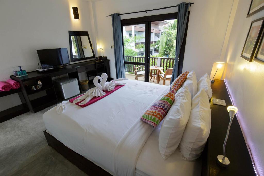 a bedroom with a bed with white sheets and pillows at Greenlight Fisherman's Village Resort & Café in Koh Samui 