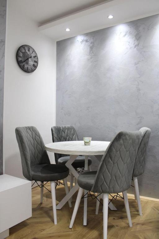 a table with chairs and a clock on a wall at IN SILVER Apartman in Vršac