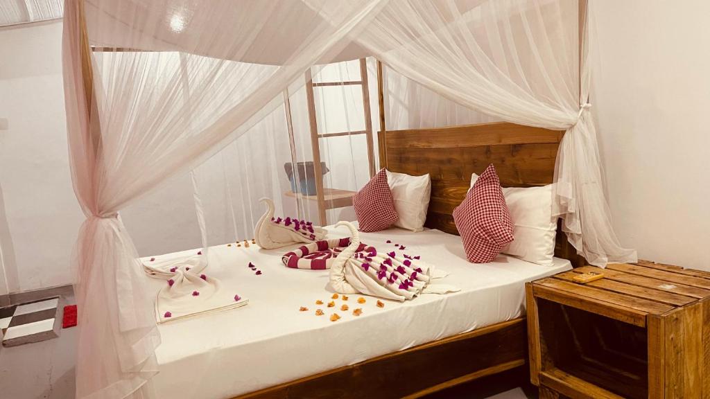 a bedroom with a white canopy bed with pillows at Swiss kiss beach resort in Uppuveli