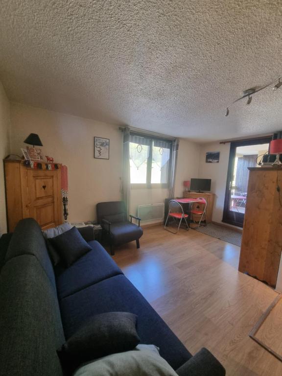 un salon avec un canapé bleu et une table dans l'établissement LE BOIS DES COQS 1 Studio 2 à 3p Serre Chevalier 1350m avec balcon 5m2 parking et casier à ski, à Saint-Chaffrey