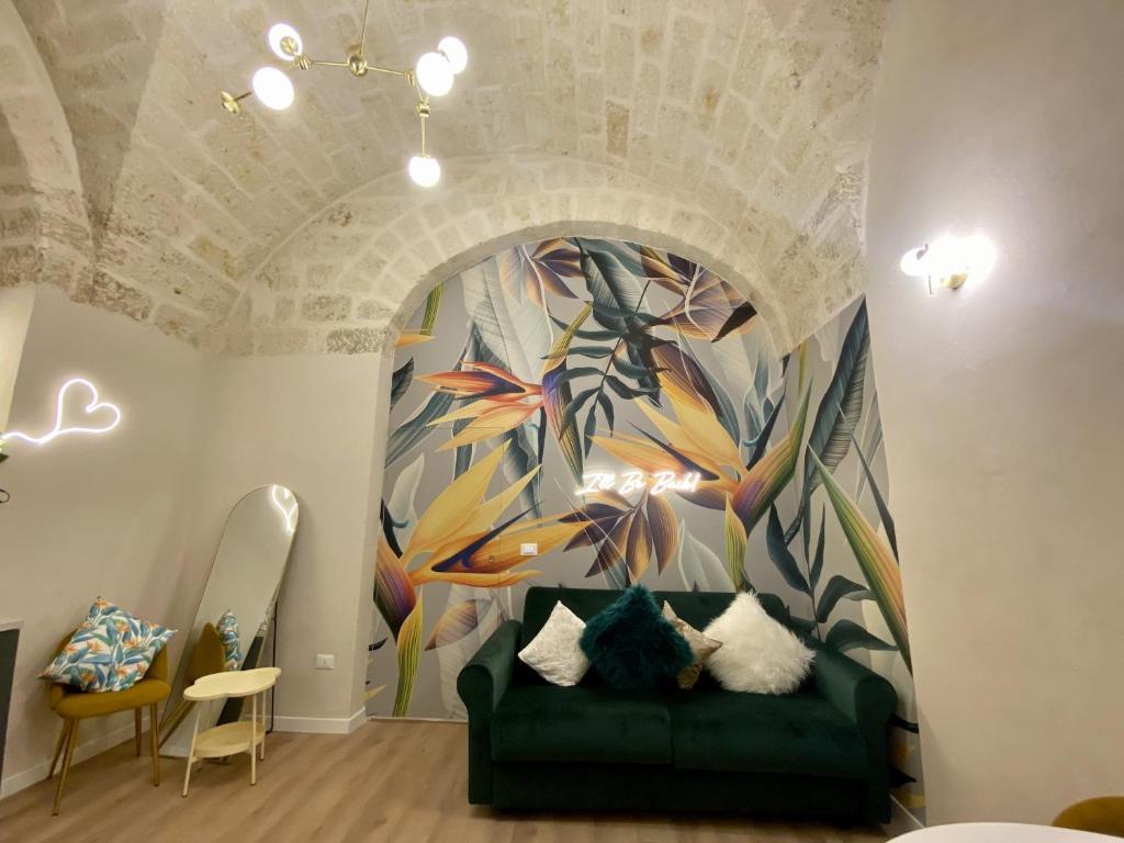 un salon avec un canapé vert devant une fresque murale dans l'établissement Quiet and stylish - Bari city center, minutes to station, à Bari