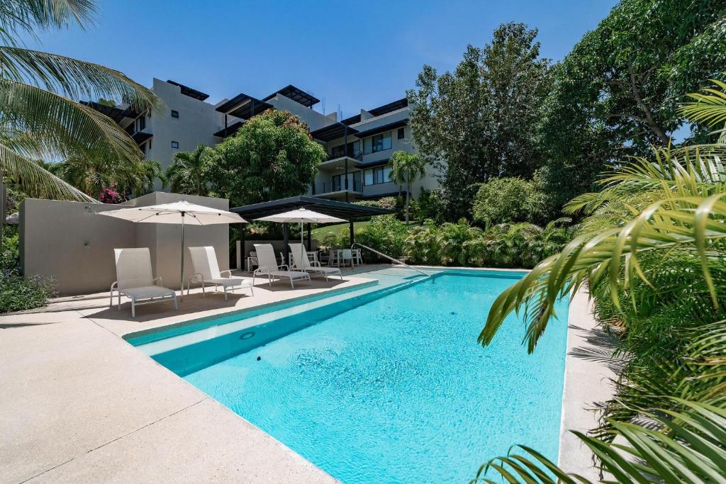 une piscine avec chaises et parasols à côté d'un bâtiment dans l'établissement 3033 - Agaves 103, à Santa Cruz Huatulco