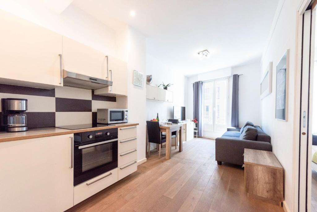 une cuisine avec des armoires blanches et un salon dans l'établissement Cannes 1-Br Apartment in the Carré d’Or, à Cannes