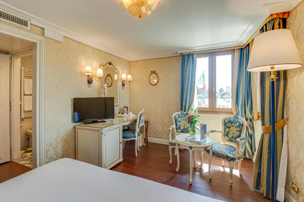 a bedroom with a bed and a desk with a television at Hotel Antiche Figure in Venice