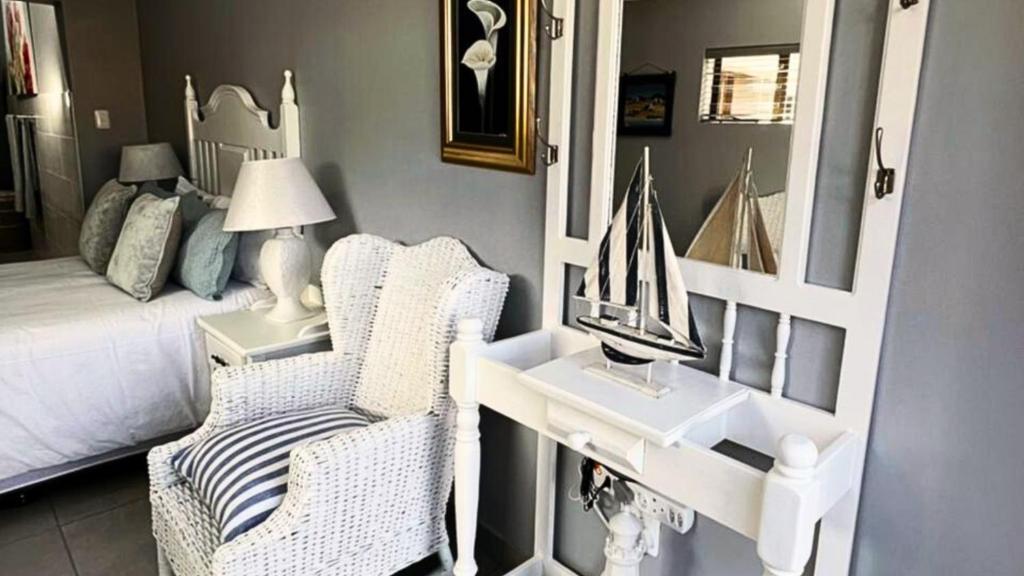a bedroom with a bed and a desk with a mirror at Vasco Diaz Beach in Mossel Bay