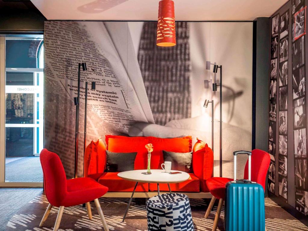 a room with a red couch and a table and chairs at ibis London Elstree Borehamwood in Borehamwood