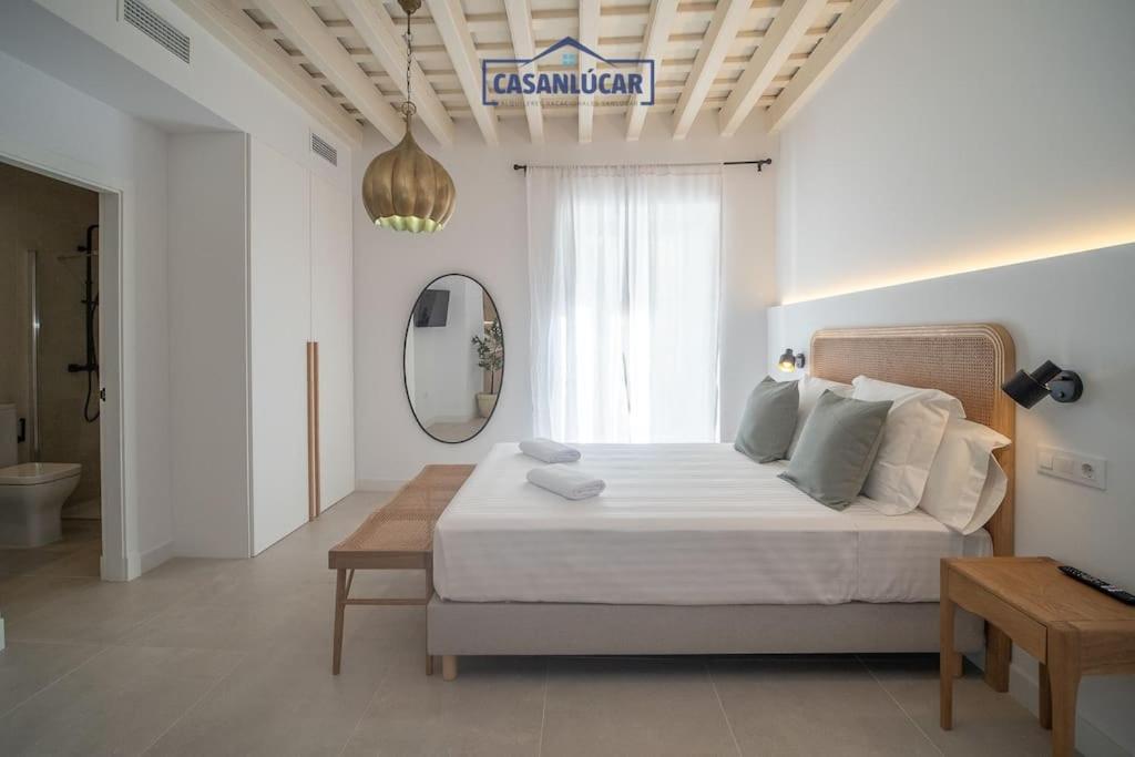 a white bedroom with a large bed and a mirror at Sanlucar Centro - Apartamento 1 in Sanlúcar de Barrameda
