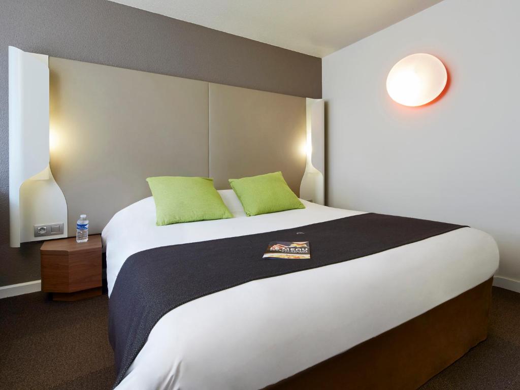 una camera da letto con un grande letto con due cuscini verdi di Campanile Tours Sud - Chambray-Les-Tours a Chambray-lès-Tours