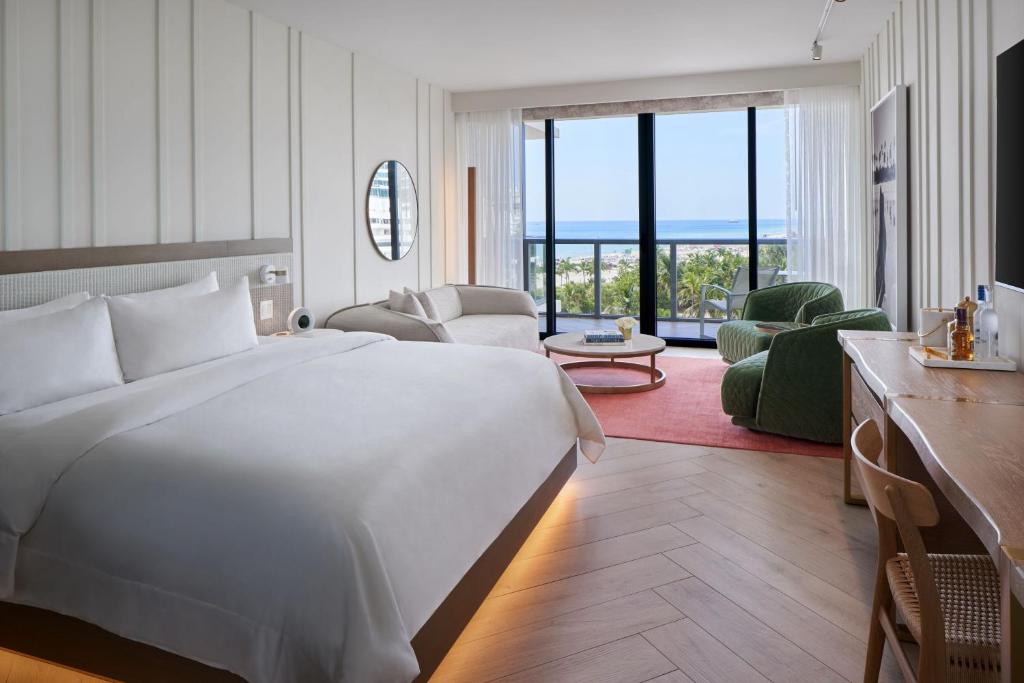 a bedroom with a large white bed and a living room at W South Beach in Miami Beach