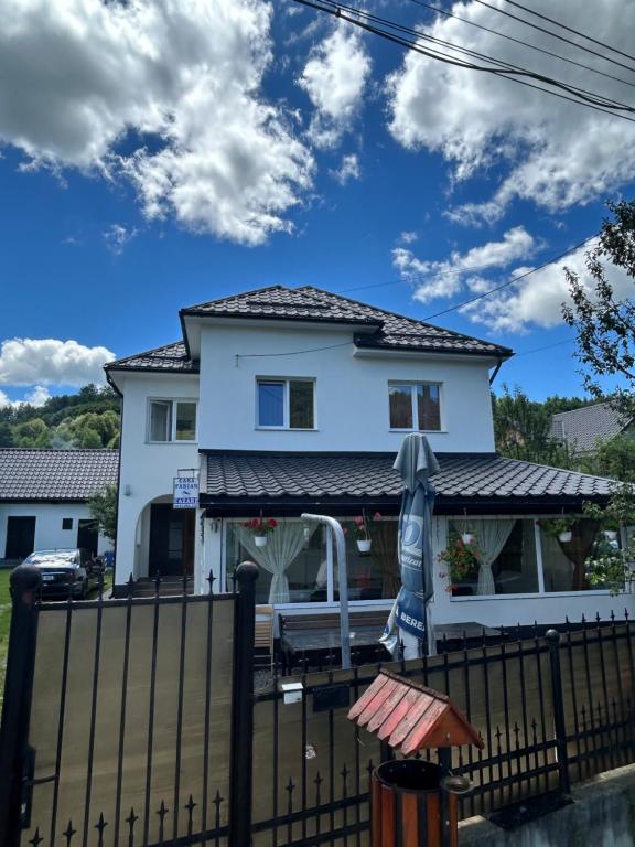 a white house with a fence and an umbrella at Casa de vacanță Fabian in Vişeu de Jos
