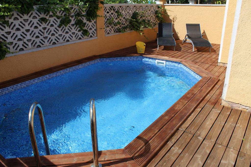 a swimming pool on a wooden deck with two chairs at Casa Montgri in Empuriabrava