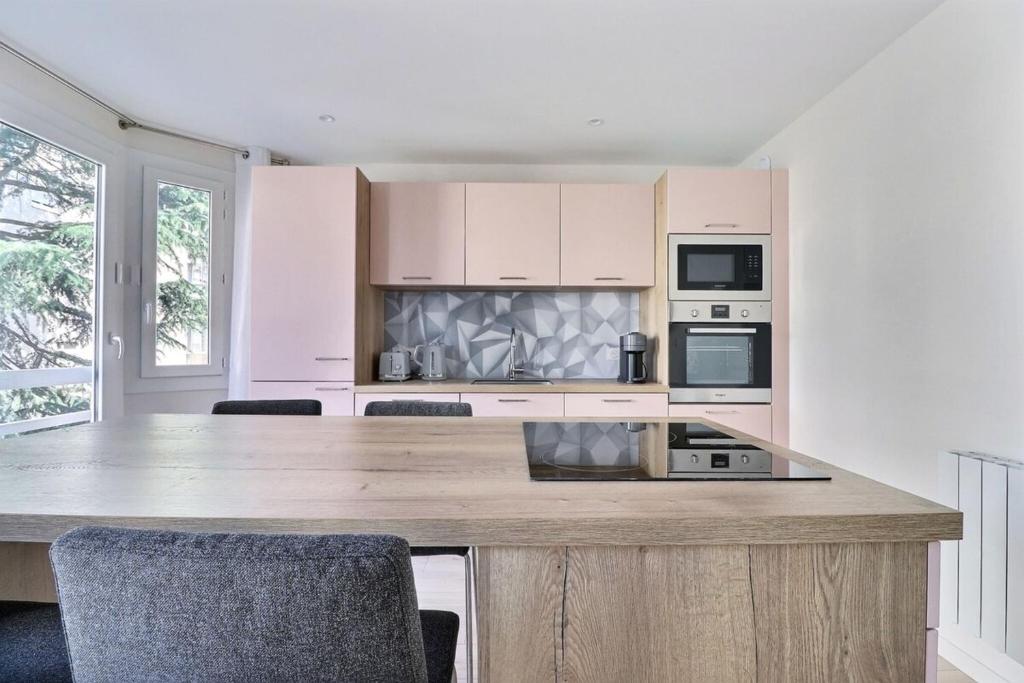 une cuisine avec un grand comptoir en bois et des chaises dans l'établissement The Monplaisir - Magnificent T2 apartment - Lyon 8th, à Lyon