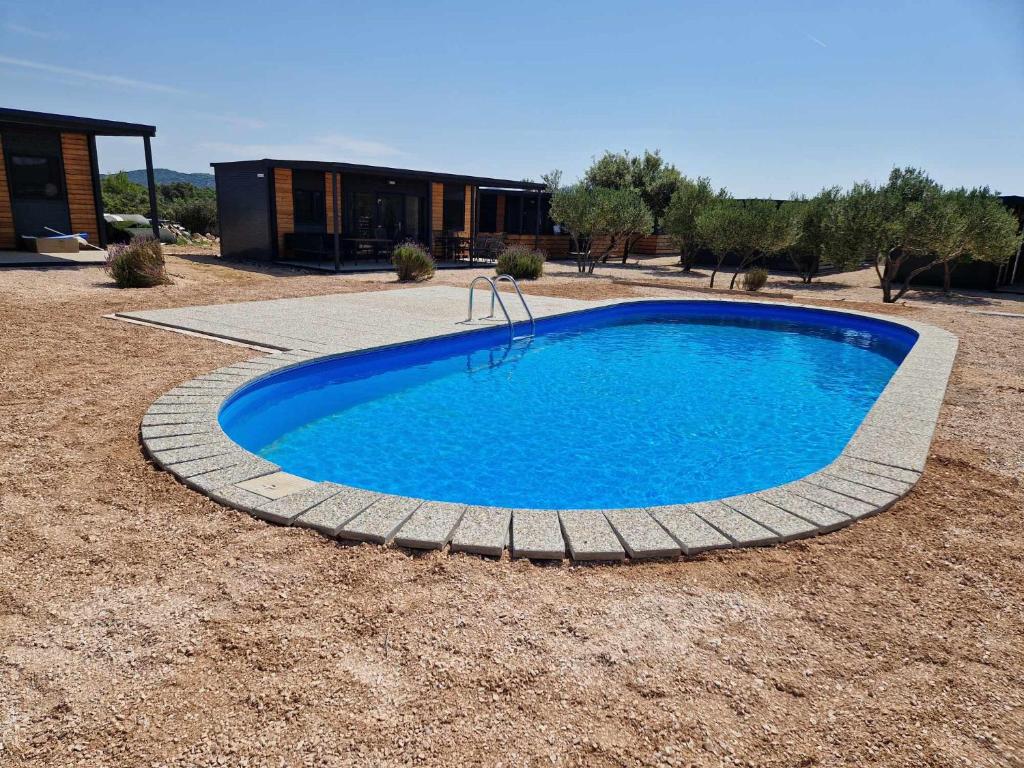 a large blue pool in a yard with a building at Mobile Home Elica, Pirovac in Pirovac