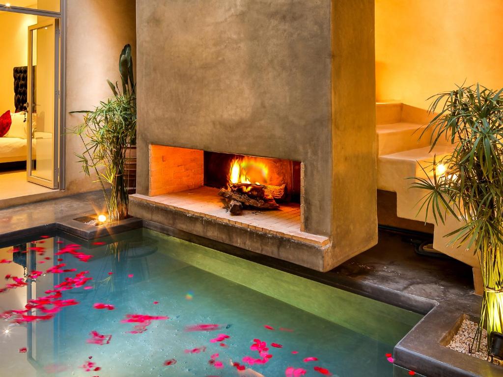 a swimming pool with a fireplace in a house at Ryad Marrakech in Marrakesh