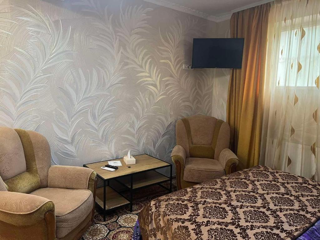 a room with a bed and two chairs and a table at Golden Rose in Chişinău