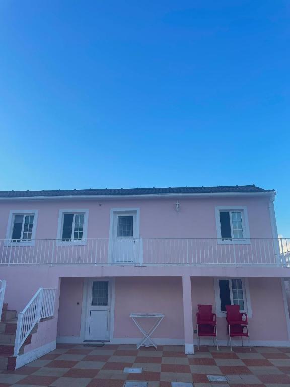 a white building with two red chairs on the balcony at Casa mãe in Lajes do Pico