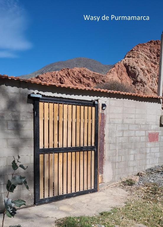 a wooden gate on a brick building with mountains in the background at Wasy de Purmamarca in Purmamarca