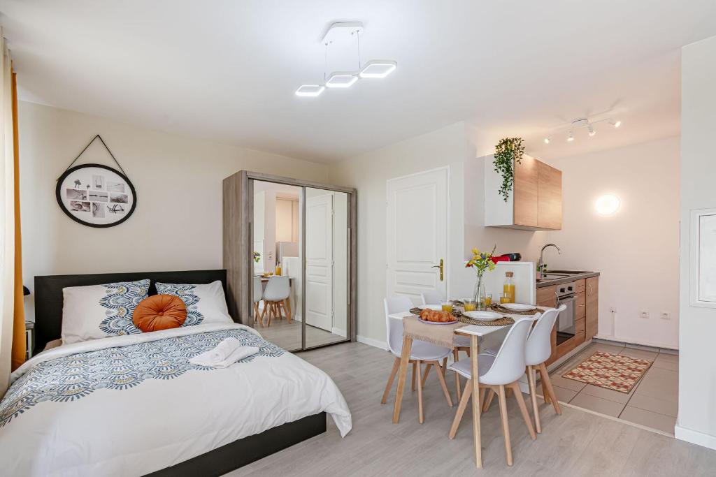 a bedroom with a bed and a table and a kitchen at COSYHOME - Studio Familial Confortable - Paris - CDG - Parking privé in Aulnay-sous-Bois