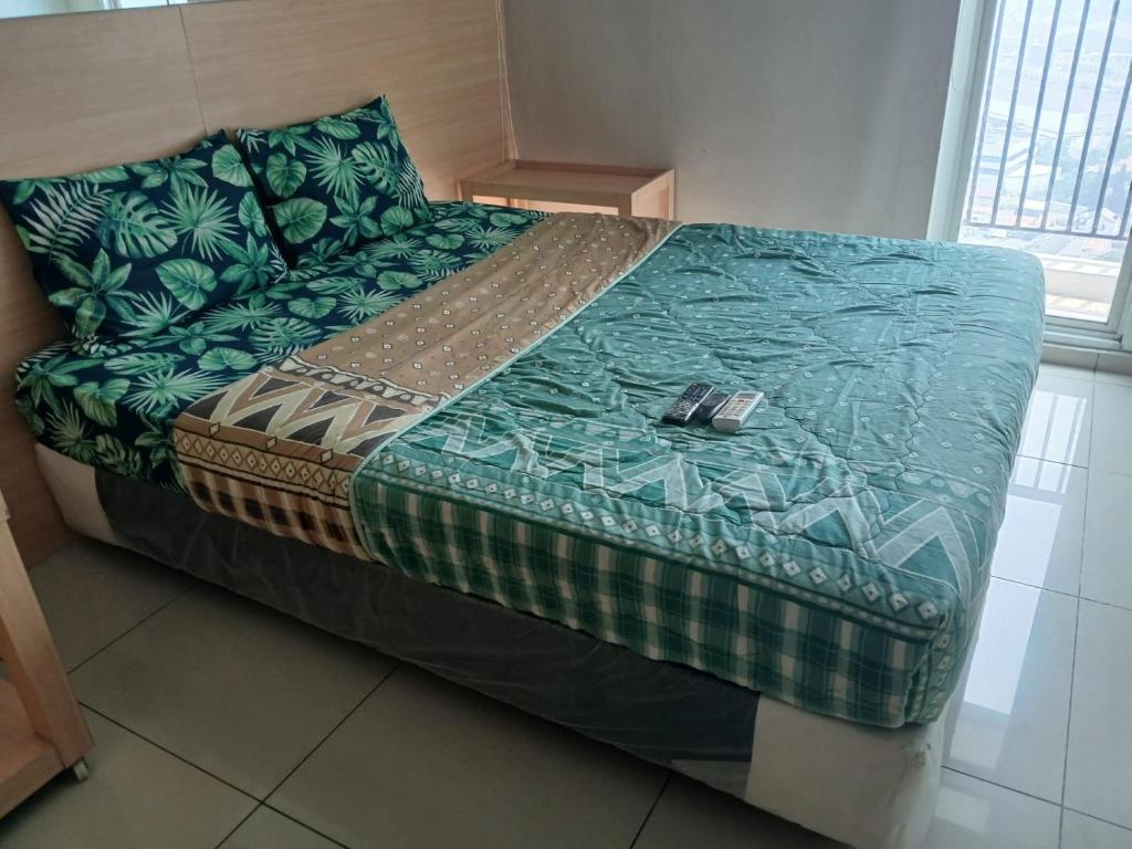 a large bed in a room with a green blanket at Treepark City Cikokol BY G-ROOM in Kebun Nanas