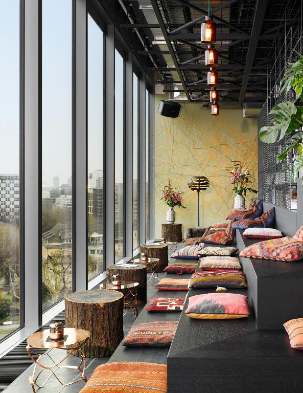 a room with couches and tables and windows at 25hours Hotel Bikini Berlin in Berlin