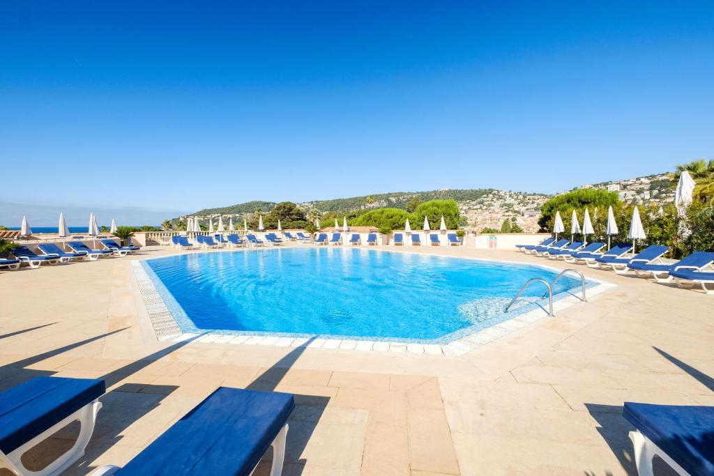 a large swimming pool with blue lounge chairs and the ocean at Résidence Pierre & Vacances l'Ange Gardien in Villefranche-sur-Mer