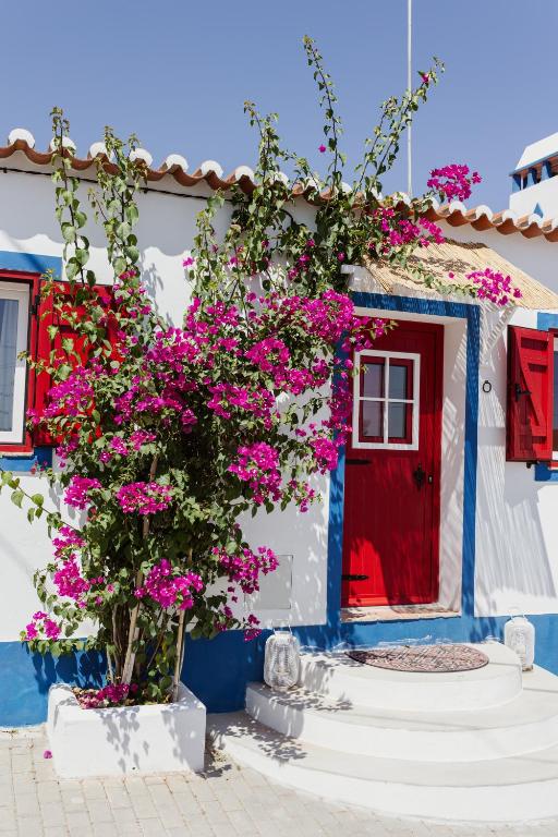 莫托拉Casa Vó Briata的房子前面的红色门和粉红色的花朵