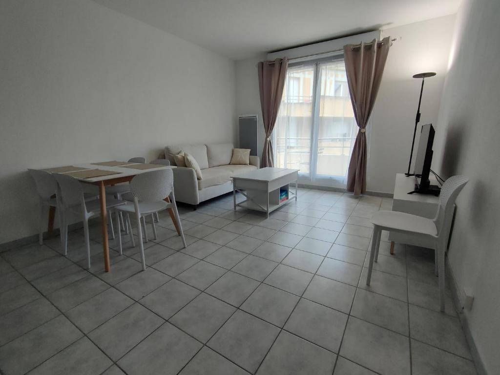 a living room with a table and a couch at Appartement - Résidence Vacances calme et tout confort in Touques