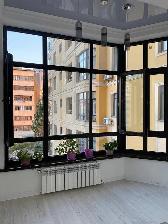 a room with a large window with potted plants at New Cozy Apartment in Bishkek