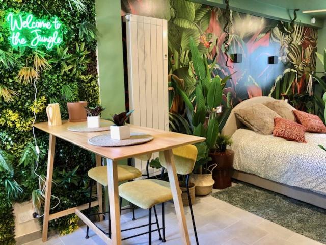 une pièce avec une table et un lit avec des plantes dans l'établissement Studio Jungle Climatisé, à Brive-la-Gaillarde