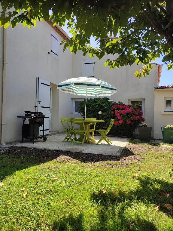 - une table et des chaises sous un parasol dans la cour dans l'établissement hortensia 8, à Saint-Étienne-de-Mer-Morte