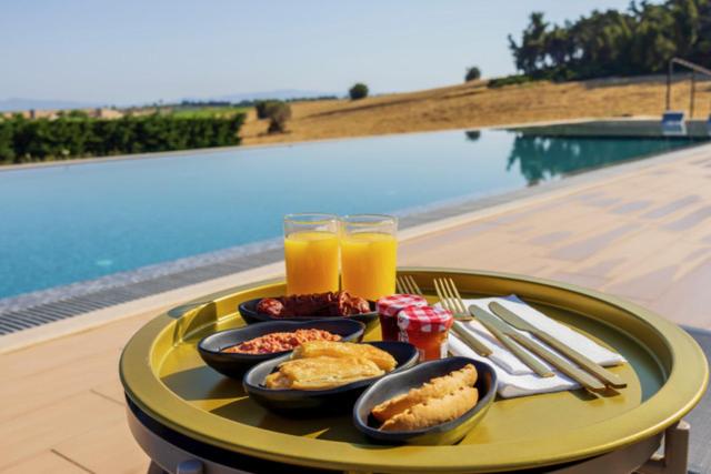 a tray with food and drinks on a table by a pool at Oikos Sani Suites in Sani Beach