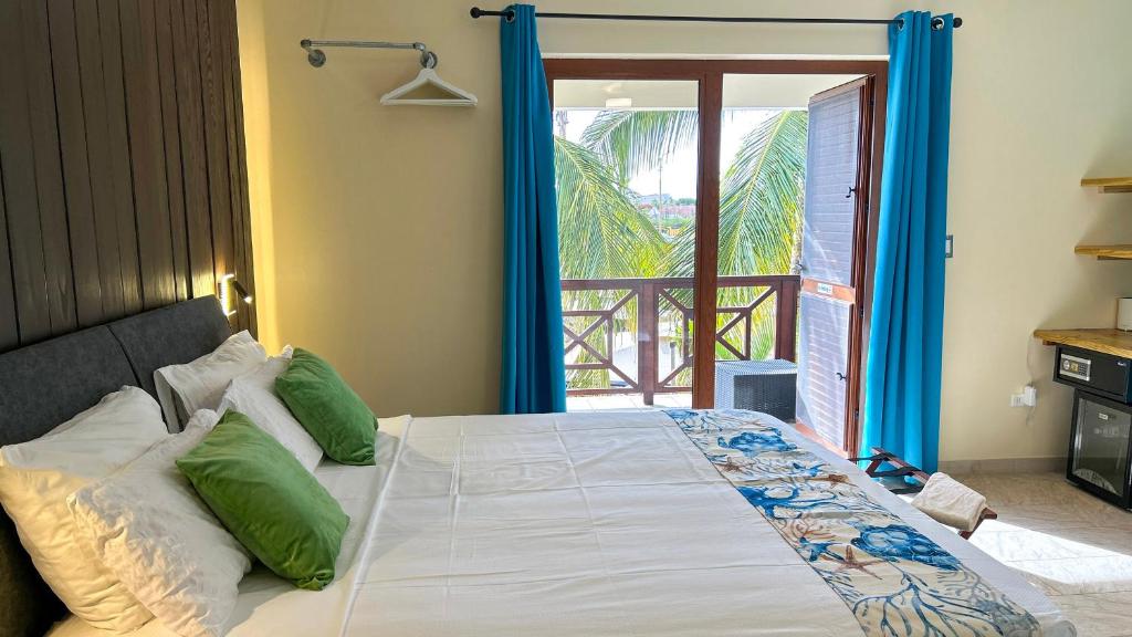 een slaapkamer met een groot bed met groene kussens bij Sonrisa Boutique Hotel - Adults Only in Kralendijk