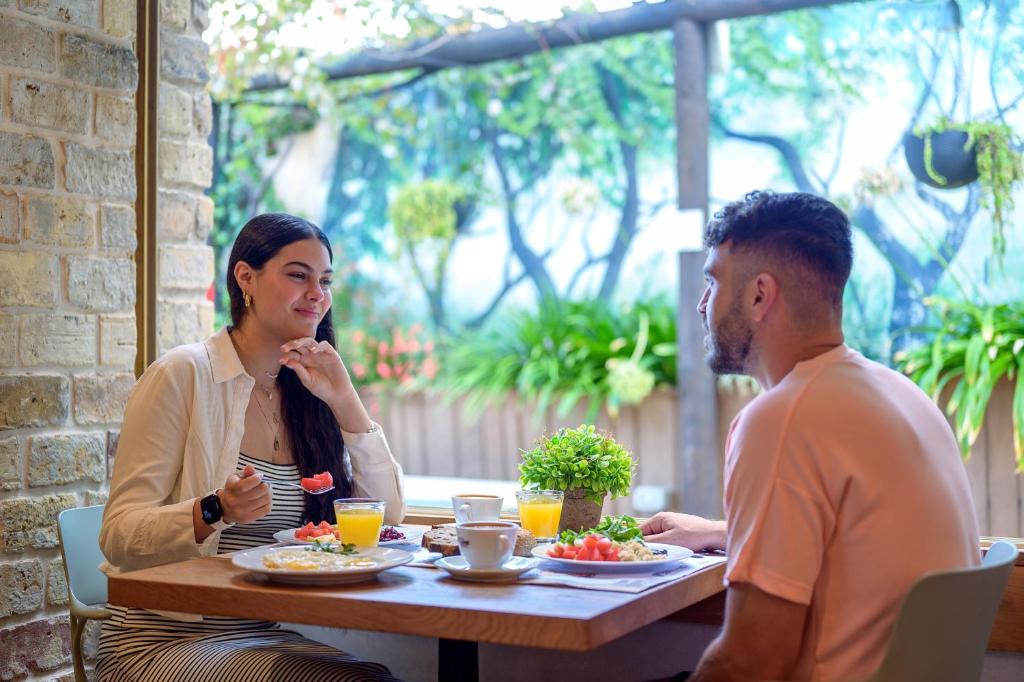 een man en een vrouw zitten aan een tafel bij Hotel Beit Maimon in Zikhron Ya‘aqov