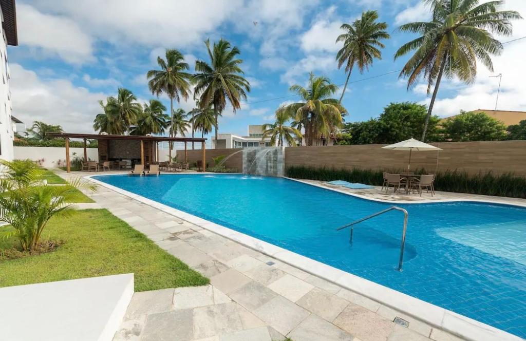 a swimming pool in a yard with palm trees at Porto de Galinhas - Apartamento 3 quartos a 30m do mar in Porto De Galinhas