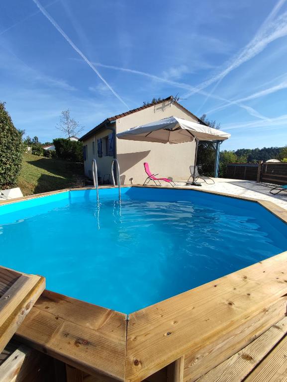 - une piscine avec une table en bois et un parasol dans l'établissement Maison privée clôturée, piscine hors-sol et spa, à Proissans